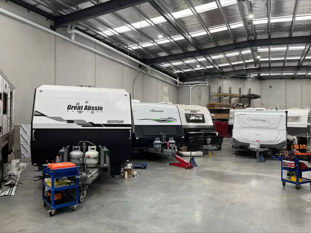 Four caravans parked inside the warehouse being repaired.