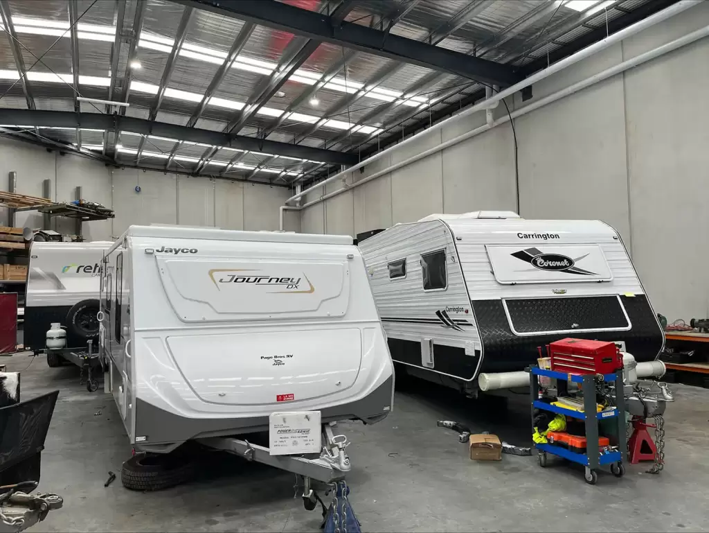 Three caravans parked inside a warehouse being repaired.