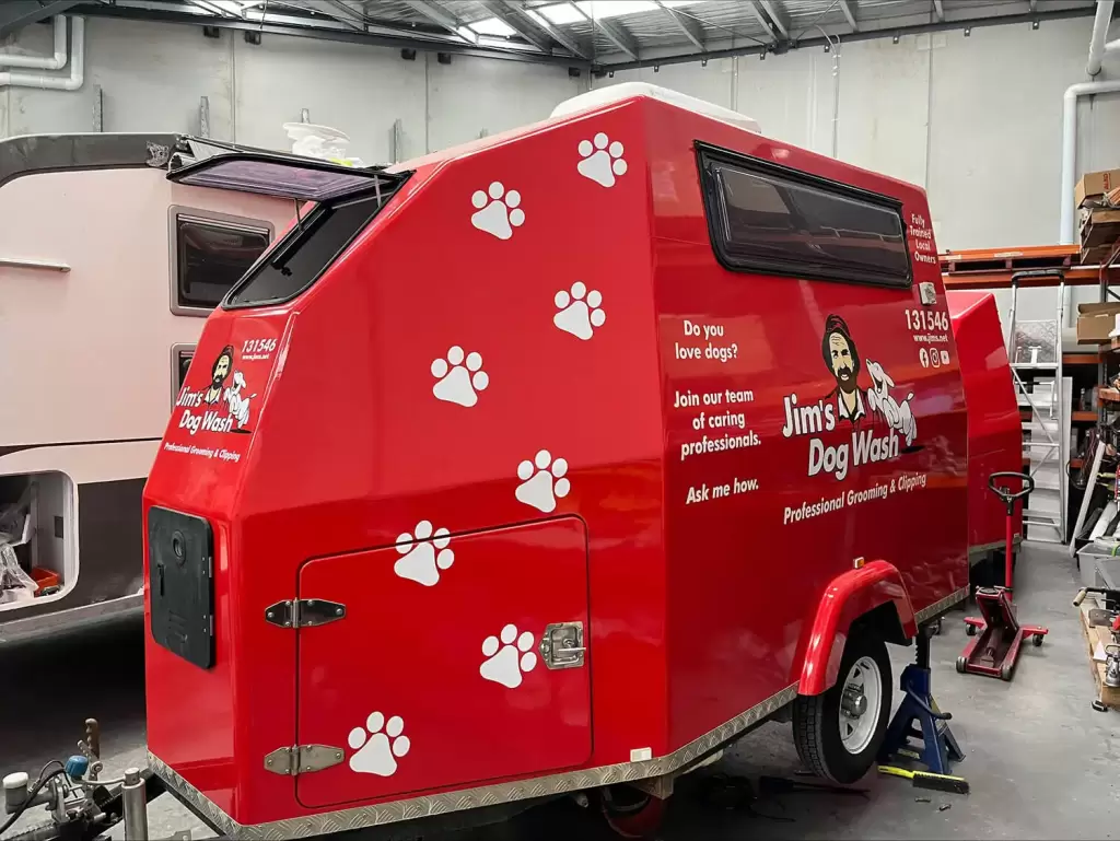 Red Jim dog wash caravan parked inside a warehouse.